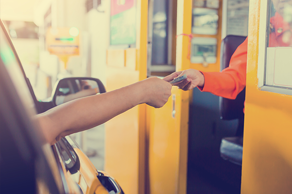 Driver in car paying cash to a toll booth