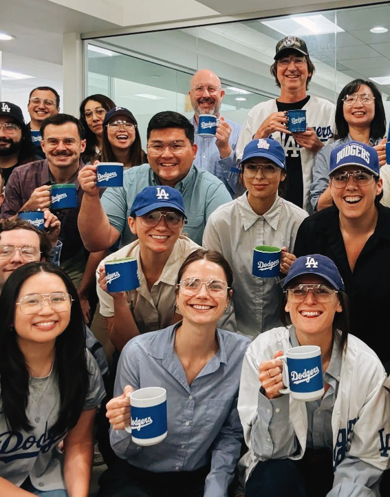 Dodgers - Page - Jan2025 LA staff pose with Dodgers hats, cups and jerseys