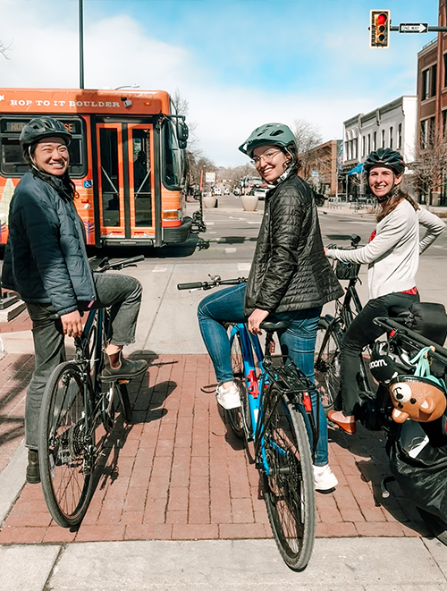 Three bicyclists stopped at an intersection and posing for a photo
