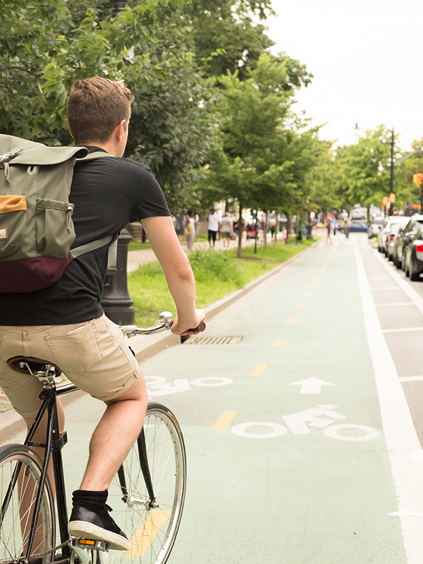 Decarbonization Header - post - July2023 Man rides bike in bike lane with cars parked alongside the lane
