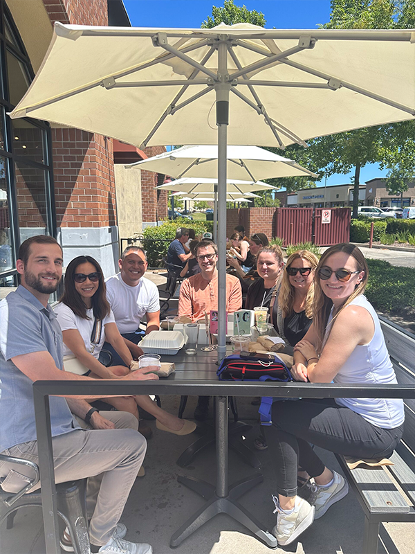 Empowering Future Talent Header - post - Apr2025 Staff posing for a photo over lunch outside at a cafe