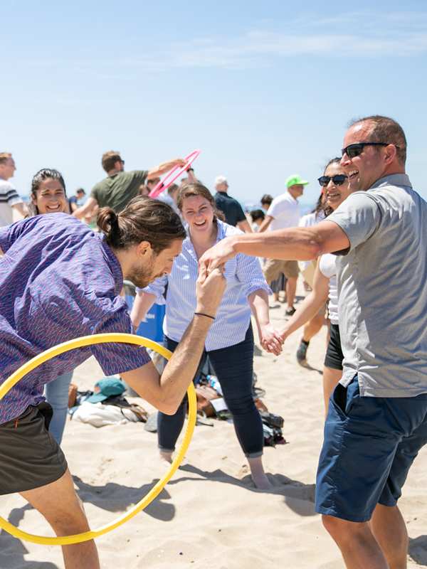 Group of staff bond and laugh over games on the beach