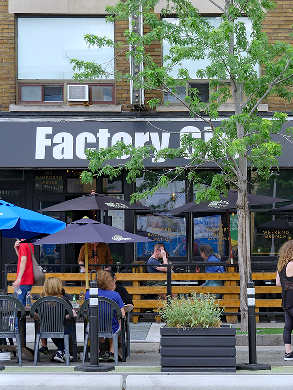Cafe with seating tables placed beside the curbside with safety barriers
