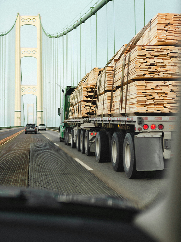 Header Image - Achieving Freight Greenhouse Gas Goals - Post - July2022 Freight truck with heavy load of lumber on bridge