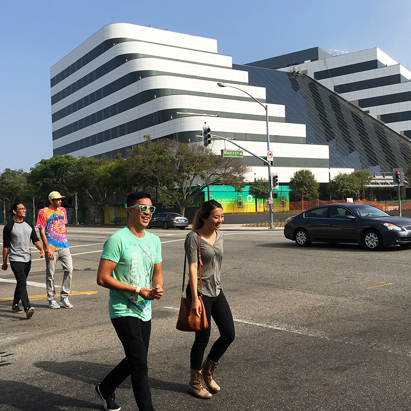 Pedestrians walk across the street as a car passes through intersection behind them