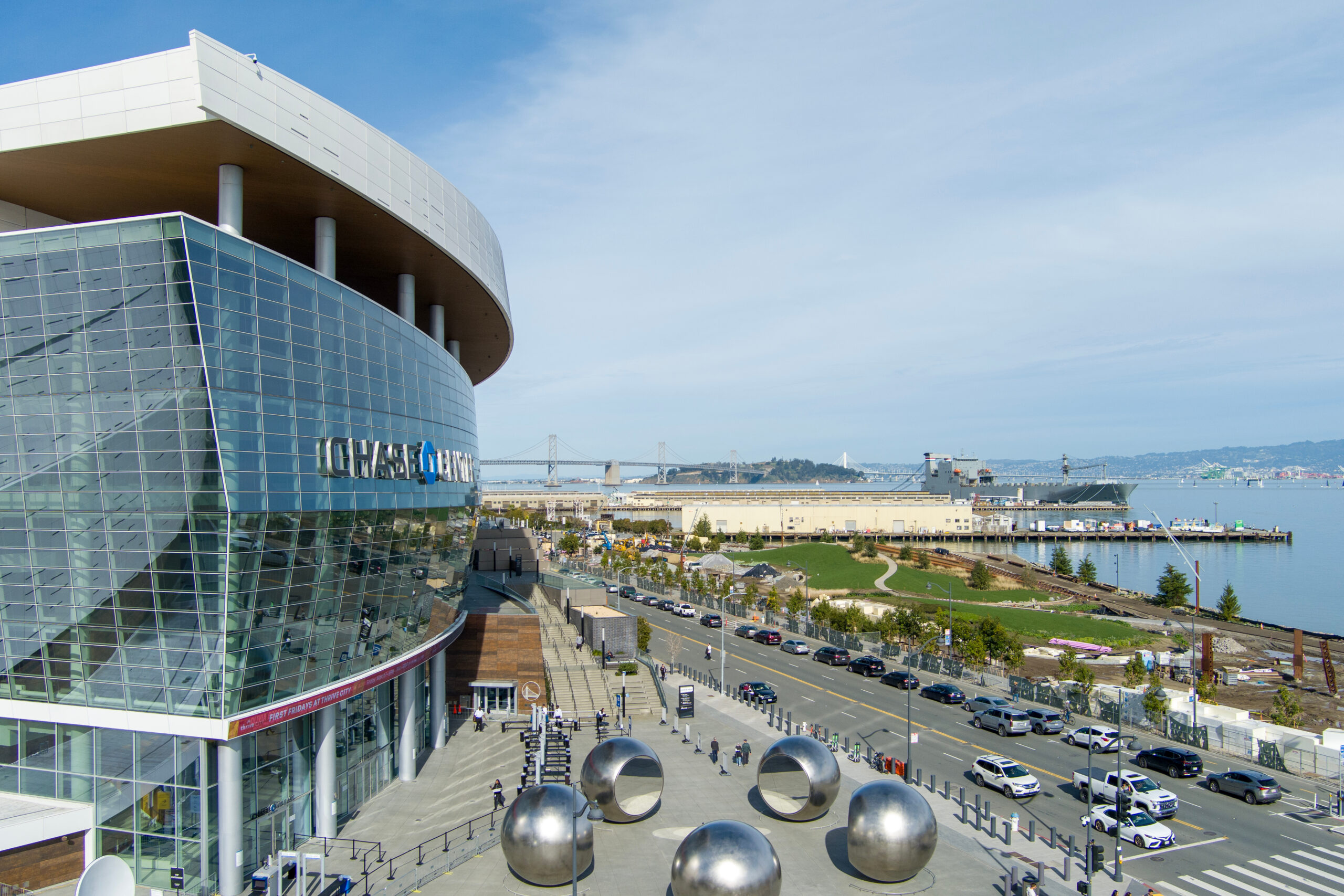 aerial shot of the Chase Center with ships on the waters of the bay and cars driving on the street, blue sky and clouds in San Francisco California USA